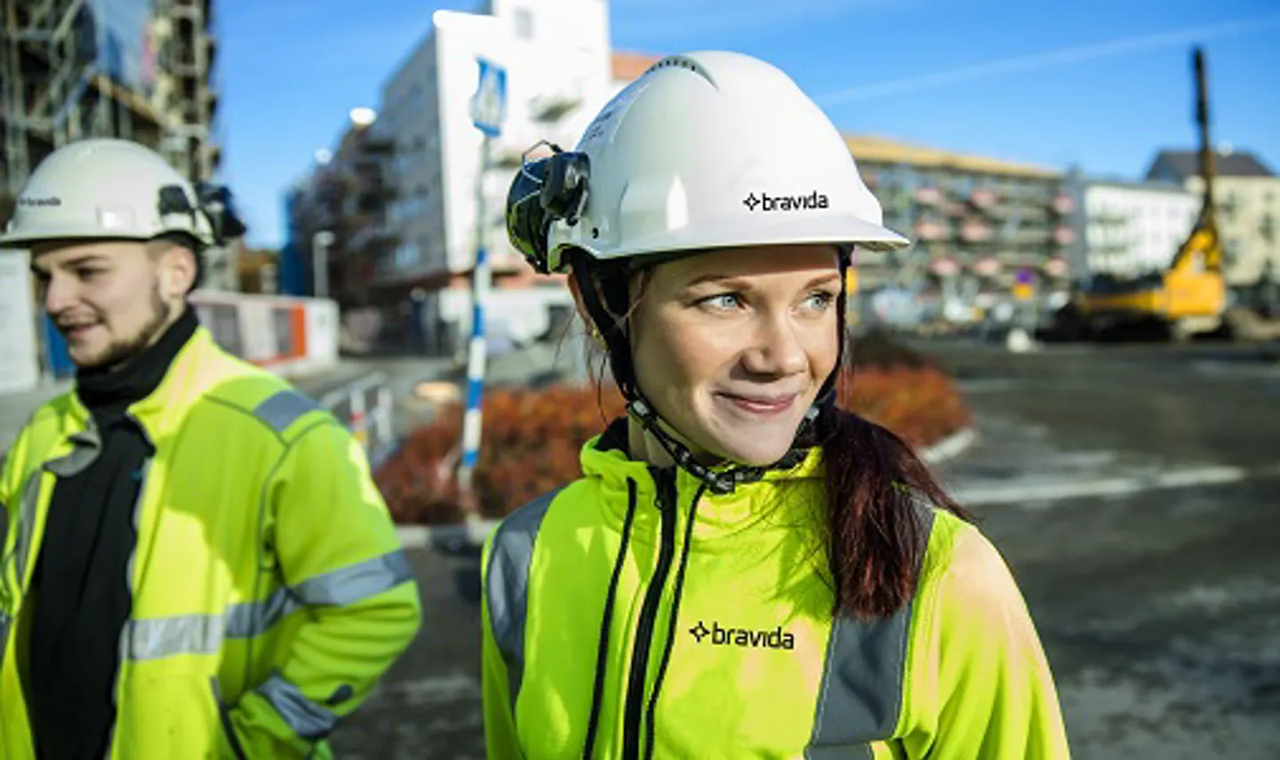 En kille och en tjej med varselkläder och hjälm på en byggarbetsplats