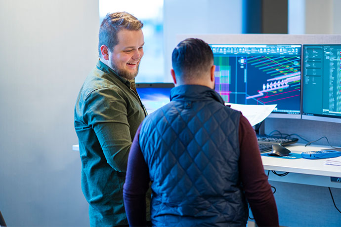 Två personer i ett samtal vid datorskärmar